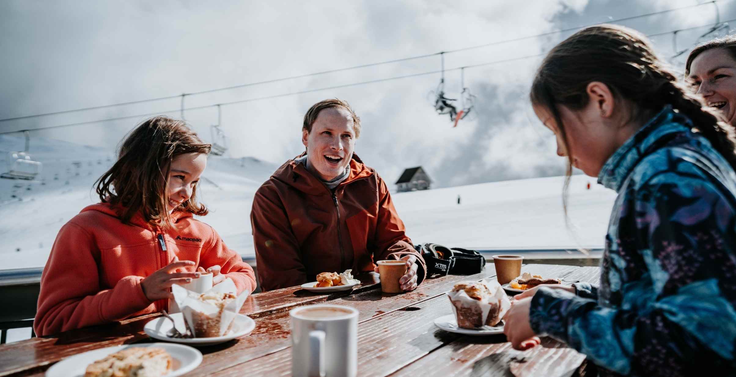 Family easting at outdoor table at a cafe at Mt Buller resort.