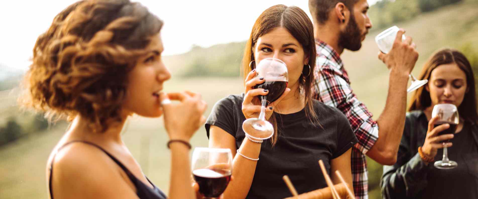 4 people drinking wine from glasses, focuing on the two women at the front