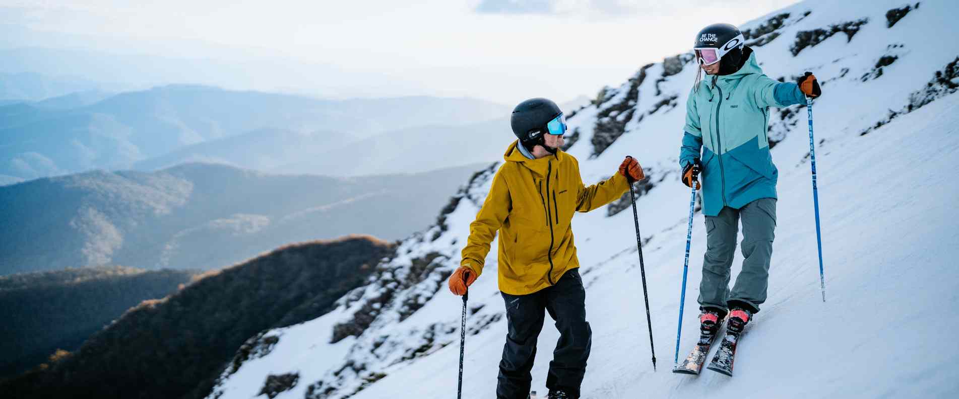 A man and woman on a snowy steep hill siking at Mt. Buller.